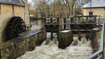 A water mill with a wooden structure and a stone building nearby.