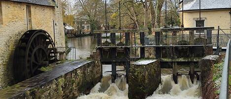 A water mill with a wooden structure and a stone building nearby.
