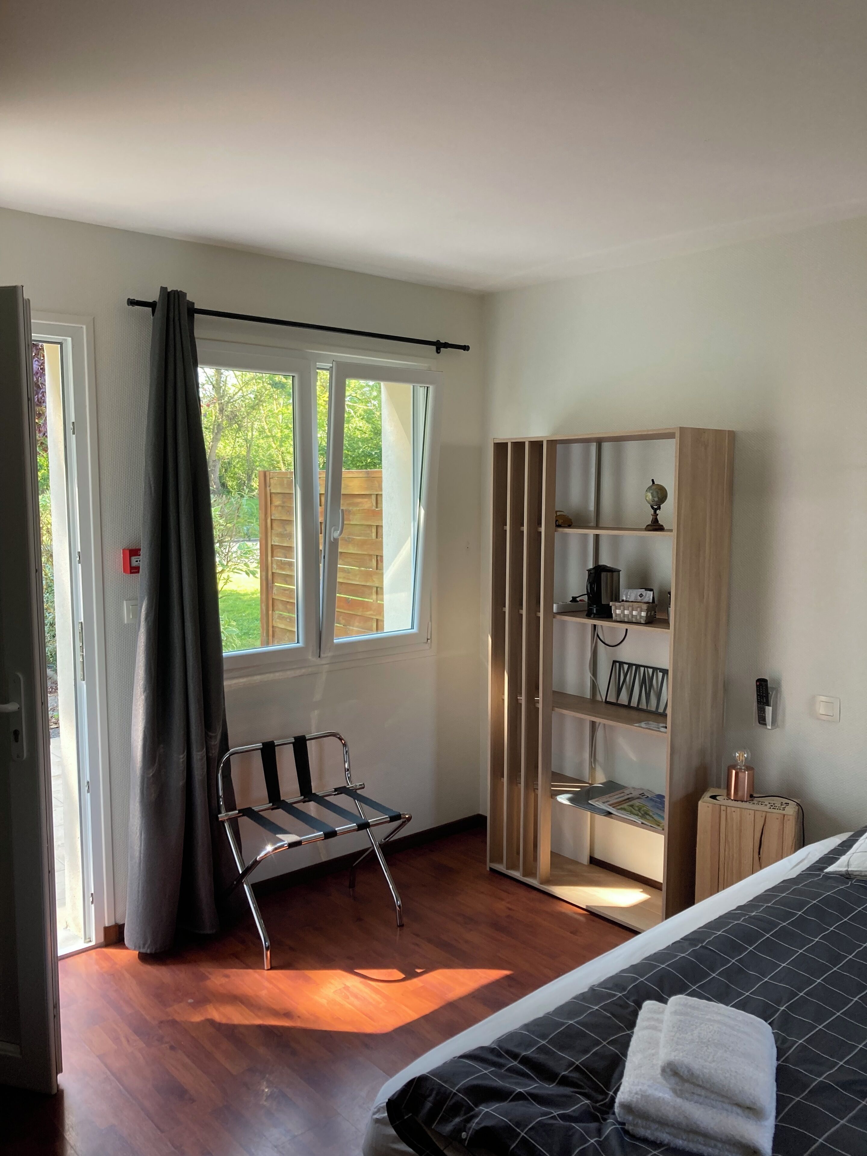 Une chambre à coucher avec un lit, une chaise, une armoire et une fenêtre avec des rideaux.