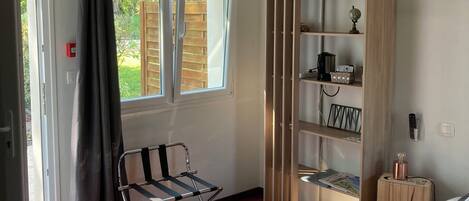 A bedroom with a bed, a chair, a wardrobe, and a window with curtains.