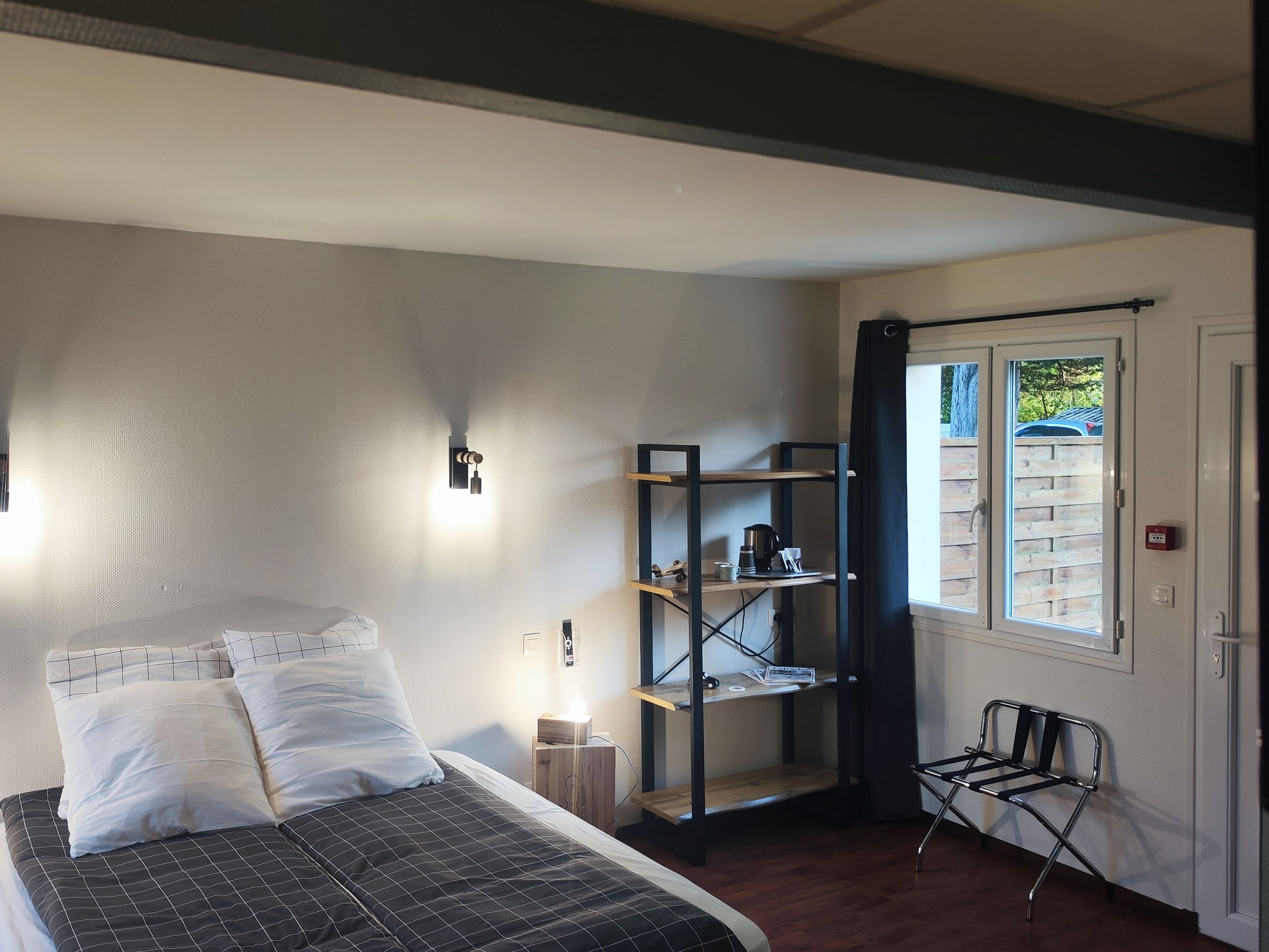 Un dormitorio con cama, un escritorio con estantes, una silla y una ventana con cortinas.