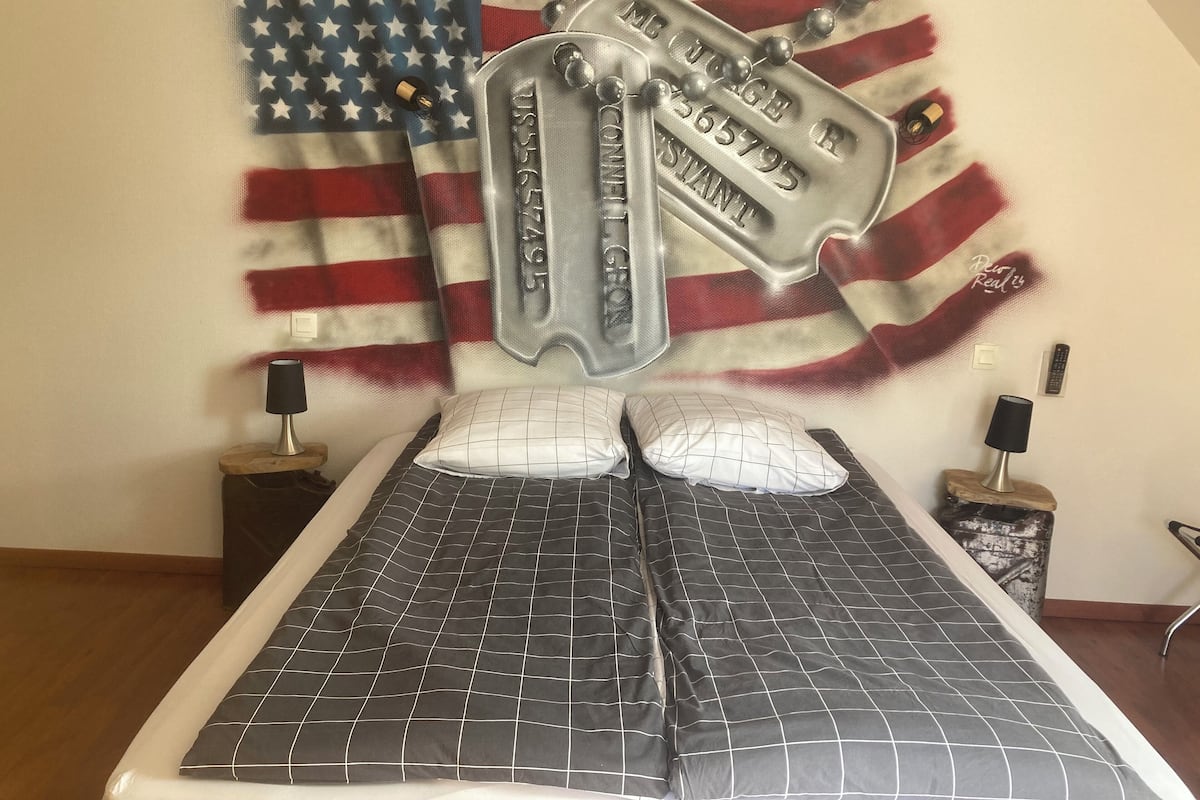 A bed with a black and white checkered bedspread, a pillow, and a headboard with a metallic plaque.