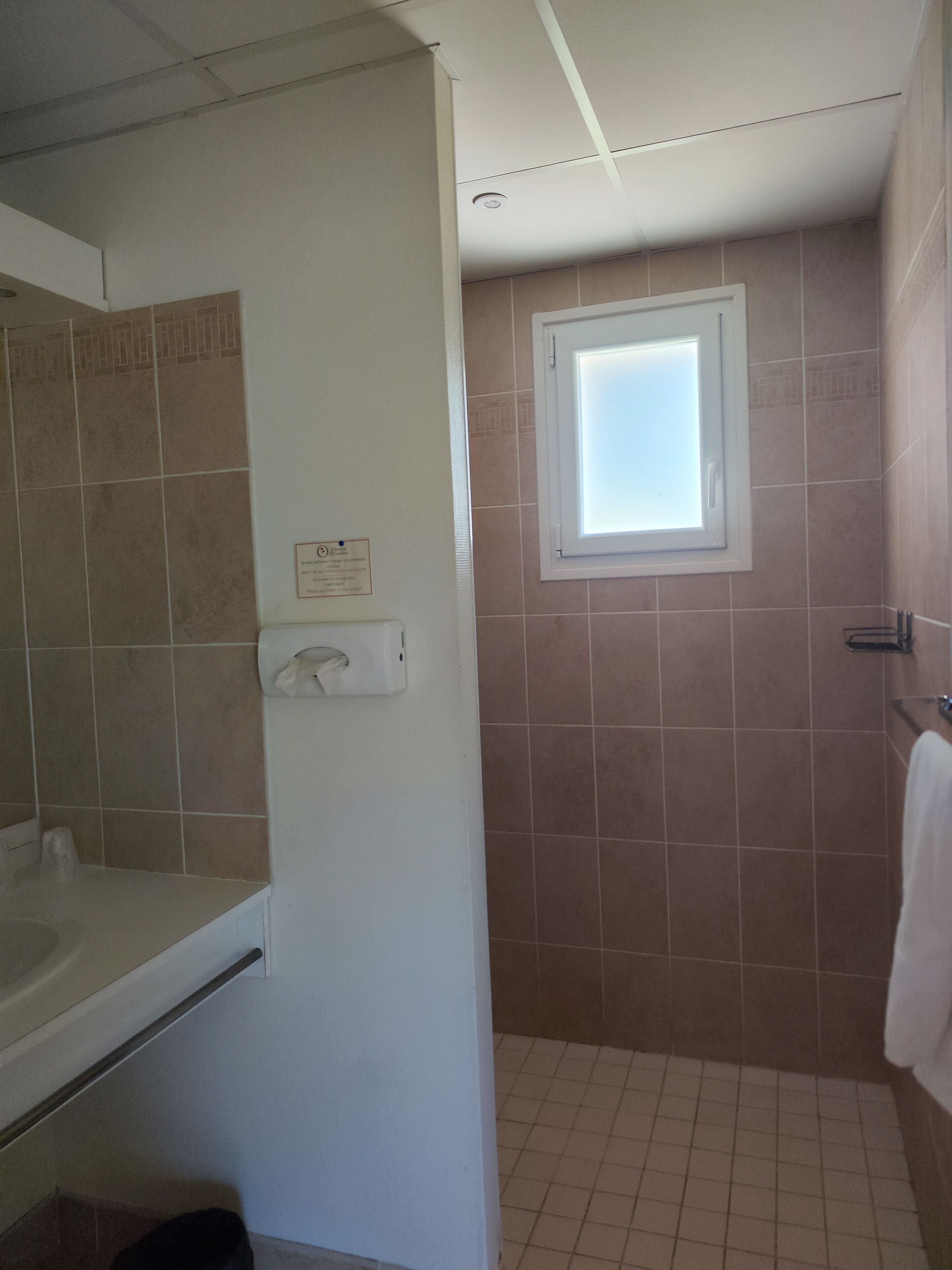 Une salle de bain avec une baignoire, une fenêtre et un porte-serviettes.