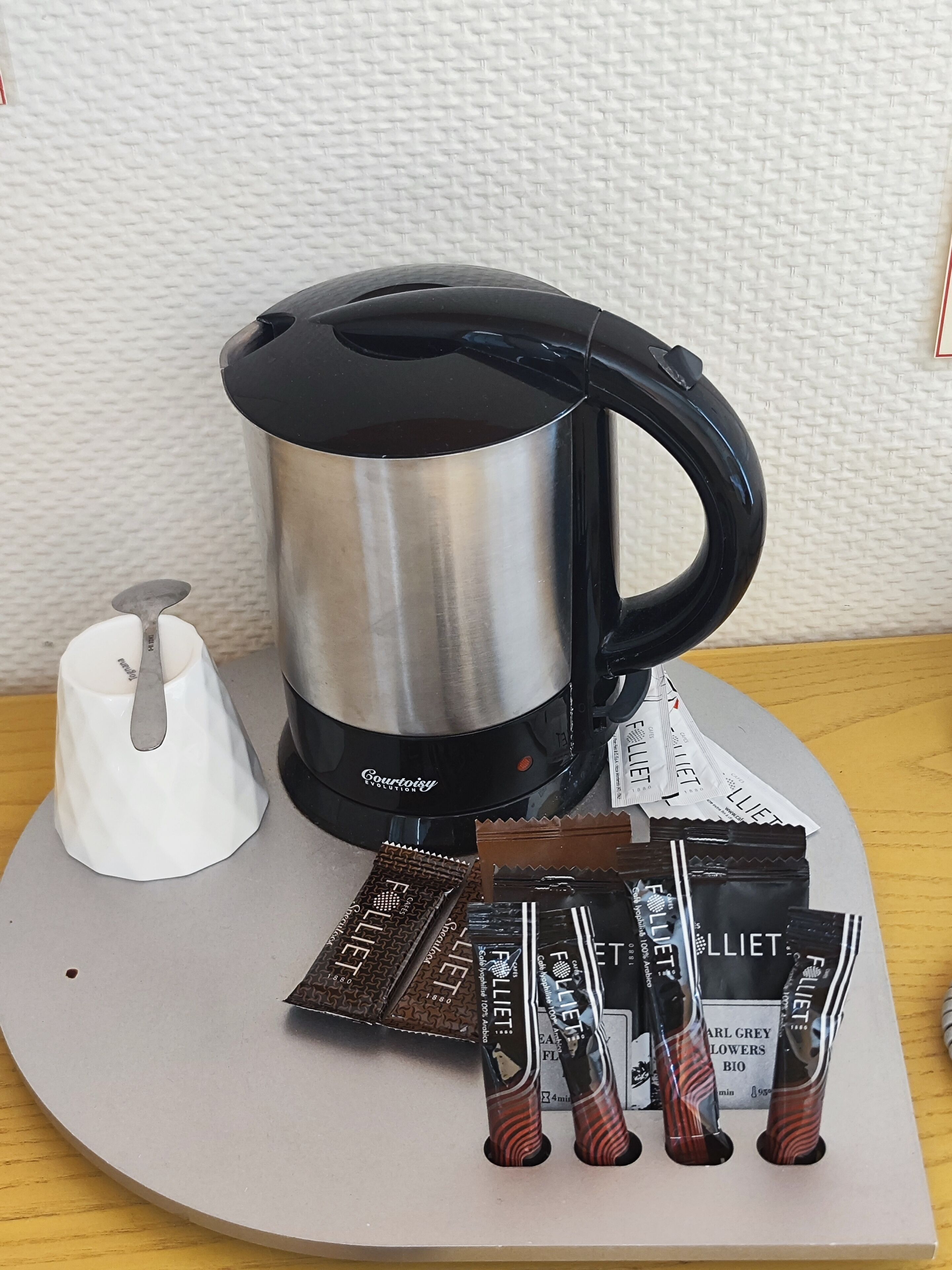 A coffee maker, a white napkin holder, and several chocolate bars on a table.