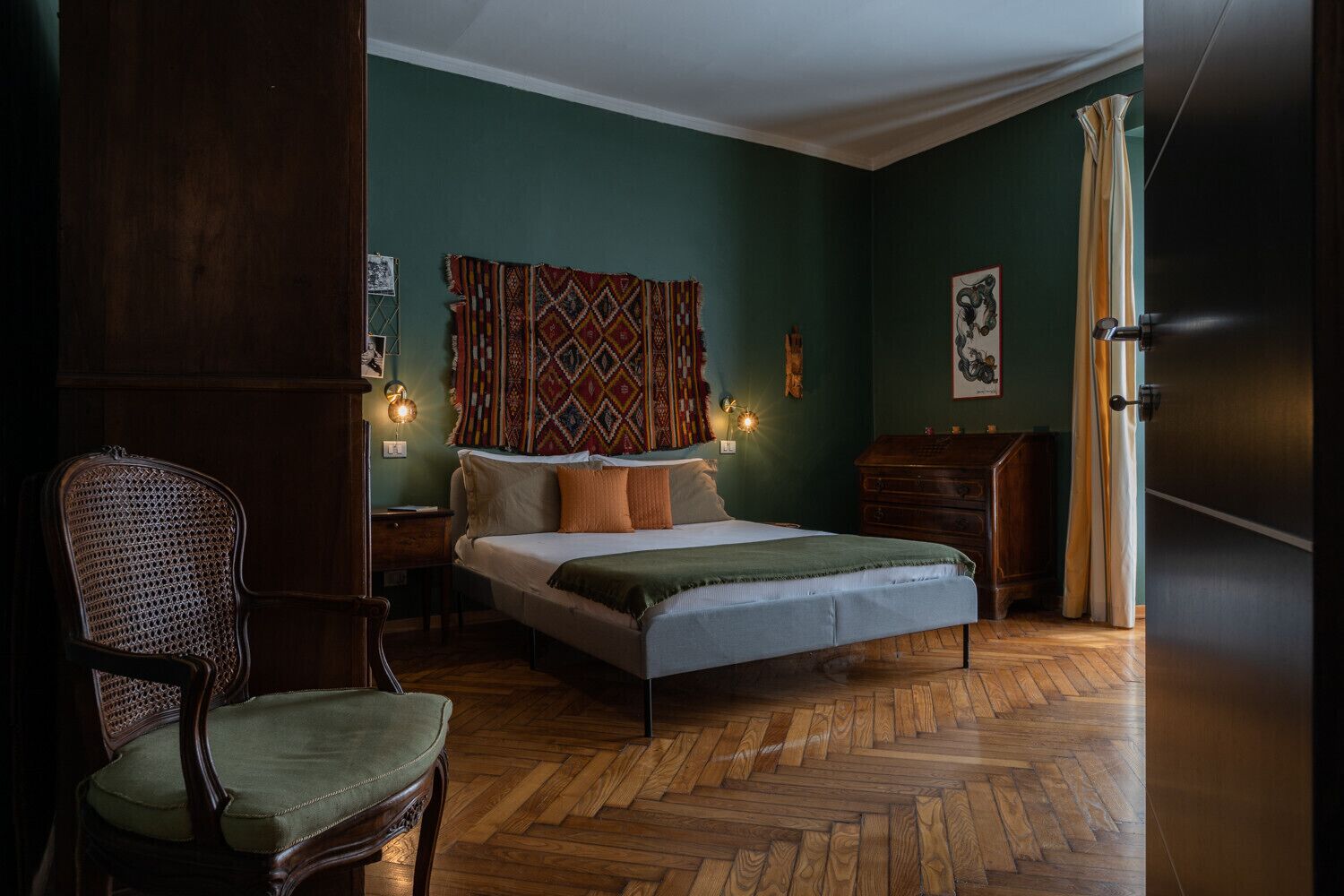 A bedroom with a bed, a chair, a dresser, and a curtain.