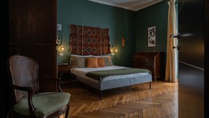 A bedroom with a bed, a chair, a dresser, and a curtain.