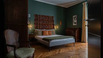 A bedroom with a bed, a chair, a dresser, and a curtain.