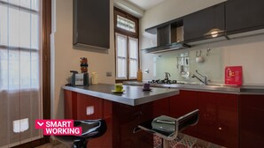 A modern kitchen with a central island, stainless steel appliances, and a red backsplash.