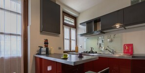 Una cocina moderna con una isla central, electrodomésticos de acero inoxidable y un salpicadero rojo.