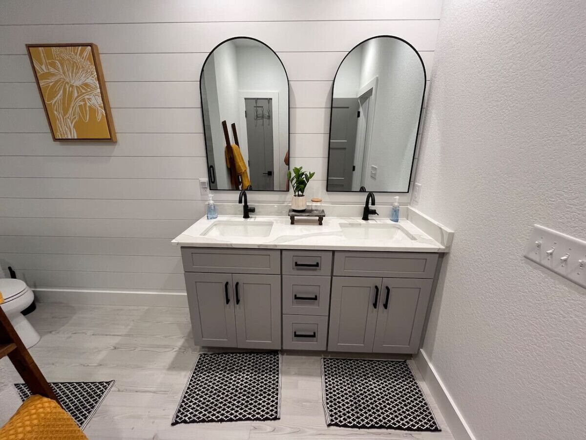 A bathroom with two sinks, a mirror, and a toilet.