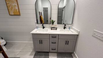 A bathroom with two sinks, a mirror, and a toilet.