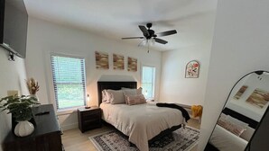 A bedroom with a bed, nightstands, a dresser, a ceiling fan, and a large mirror. - The Crepe Myrtle Cottage (Franklin)