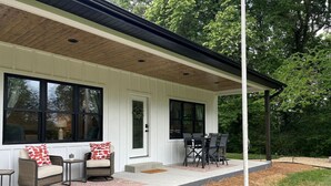 A covered patio with outdoor furniture, a door, and a window. - The Crepe Myrtle Cottage (Franklin)
