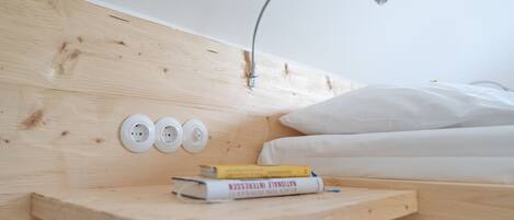 A wooden headboard with a built-in shelf, a white pillow, and a bedside lamp.