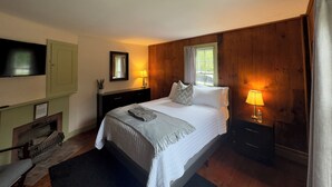 Ein Schlafzimmer mit Bett, Nachttischlampen, einem Fernseher, einem Spiegel und einem Kamin.