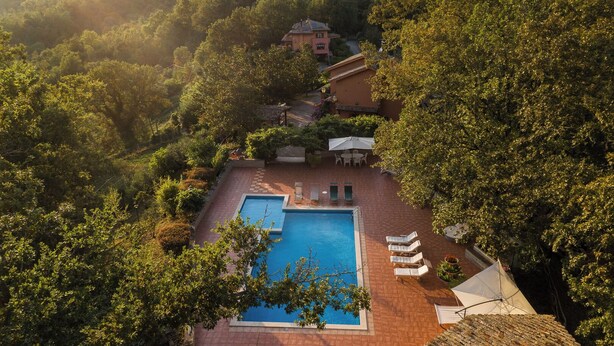 A pool area with a rectangular pool, lounge chairs, and a patio table.