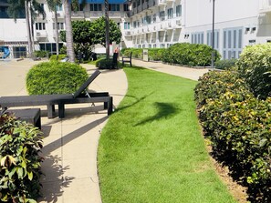 A well-maintained outdoor area with a grassy lawn, a lounge chair, and a bench.