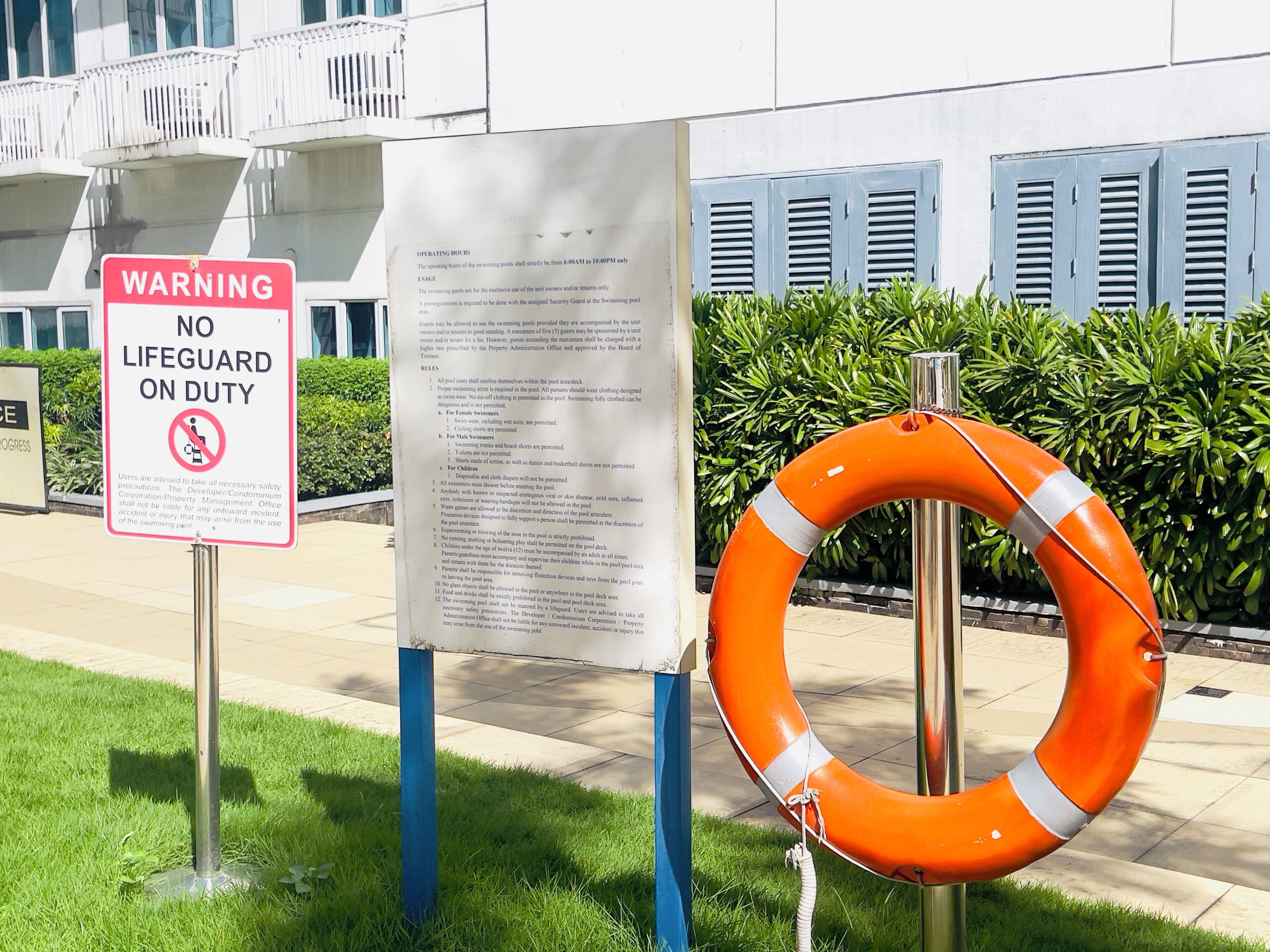 A lifeguard sign, a posted notice, and an orange lifebuoy.