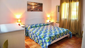 A bedroom with a bed, bedside lamps, a nightstand, a dresser, a painting on the wall, and a window with curtains. - Stazzu Fioritu trilocali vista mare (San Teodoro)