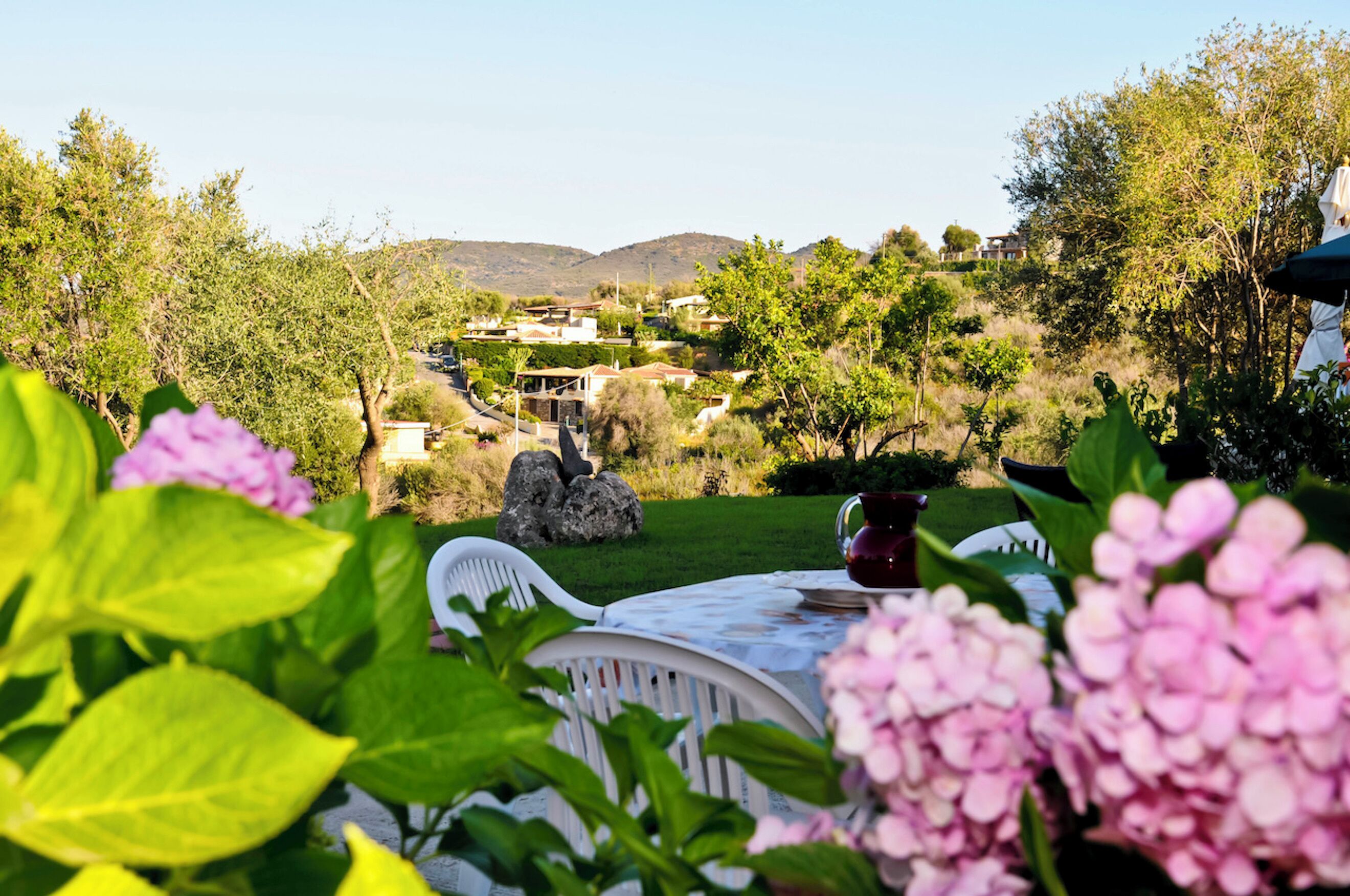 A garden view with a table, chairs, and a stone structure.