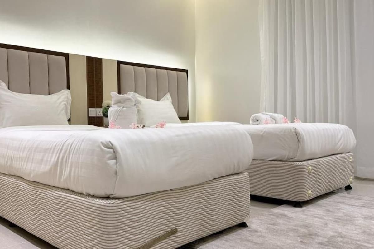 A double bed with a headboard, two pillows, a bedside table, and a nightstand.