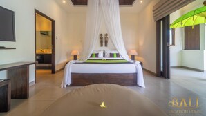 Un dormitorio con cama a dosel, lámparas de noche, cabecera de madera y vista de la habitación contigua.