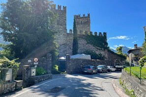 Un château en pierre avec une tour, des voitures garées et un ciel dégagé.