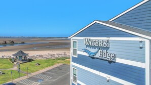 A building with a sign reading "WATER'S EDGE" and a view of a beach with a gazebo. - Top Floor, Ocean View Condo in The Heart of The Taft District in Lincoln City (Lincoln City)
