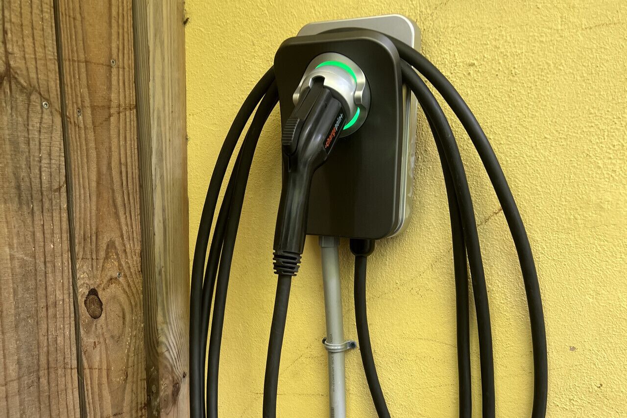 Une borne de recharge pour véhicules électriques, dotée de plusieurs câbles et fixée à un mur.