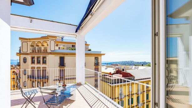 A balcony with a view of a yellow building and a distant cityscape. - Chiave di Fuga (Naples)