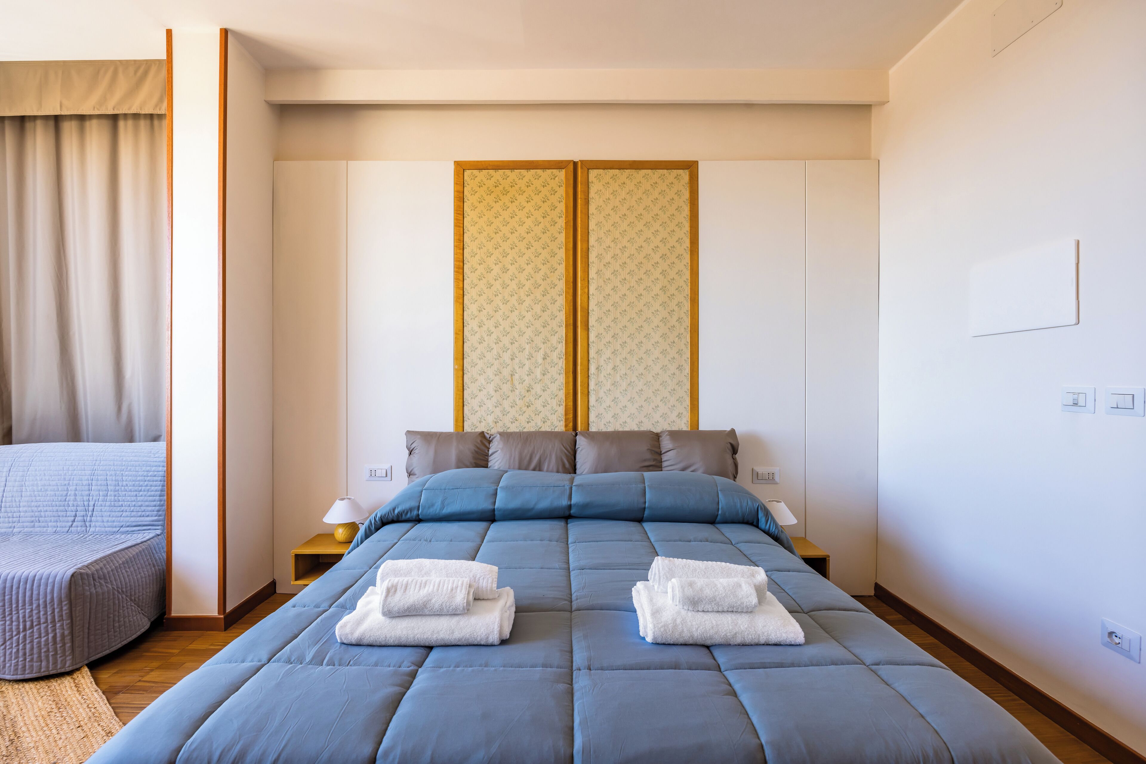 A modern hotel room with a large bed, two nightstands, a bedside table, and a view of a traditional Japanese room divider.