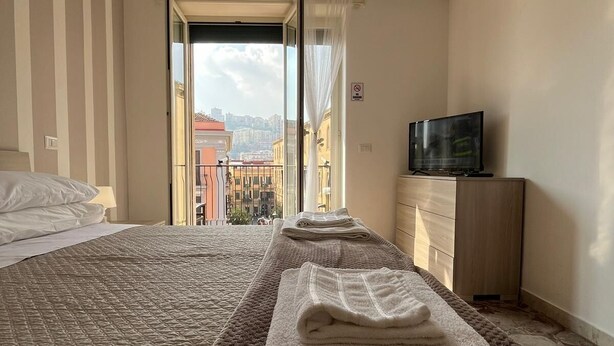 Une chambre d’hôtel avec deux lits, une télévision et un balcon donnant sur la ville.