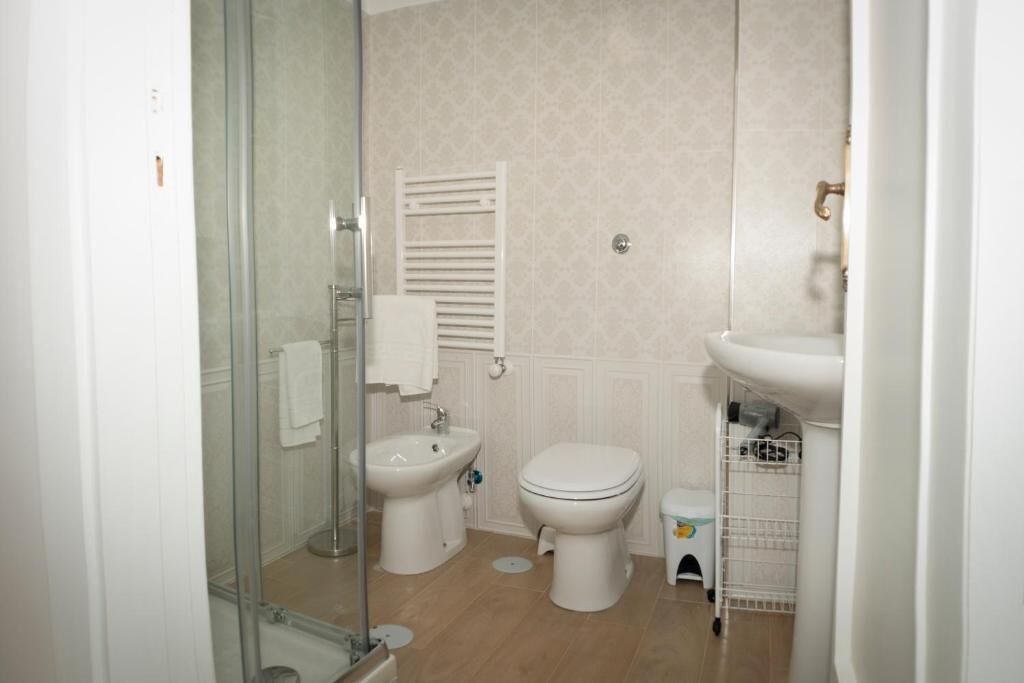 Un baño pequeño y funcional con cabina de ducha de vidrio, inodoro, bidé y lavamanos.