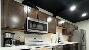 Une cuisine moderne avec des meubles en bois foncé, des appareils électroménagers en acier inoxydable et un plancher en bois.