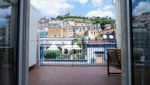 Ein Balkon mit Blick auf eine historische Festung auf einem Hügel, einem Kachelboden und einem Metallgeländer.