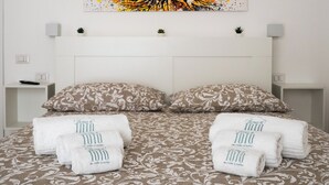 Ein Schlafzimmer mit einem Bett, zwei Kissen, zwei Nachttischen und einem Wandbild.