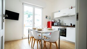 Eine moderne Küche mit weißen Schränken, einem roten Kühlschrank und einem Essbereich mit weißen Stühlen und einem Glastisch.