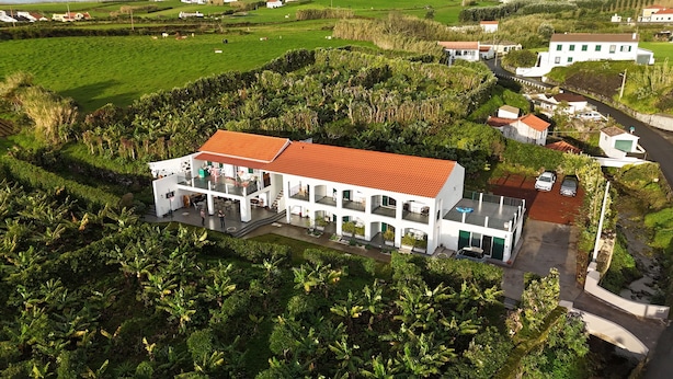A white building with a red roof, surrounded by lush greenery and fields. - AMARELO the YELLOW room (Feteira)
