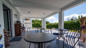 An outdoor patio area with round tables and chairs, a wooden cabinet, and a view of the garden. - AMARELO the YELLOW room (Feteira)