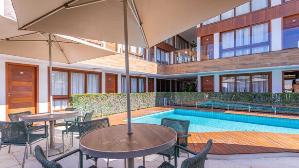Un hotel con piscina, area salotto all'aperto e un edificio a due piani.