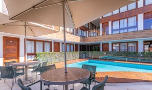 Un hotel con piscina, zona de estar exterior y un edificio de dos plantas.
