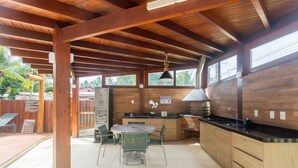 Una cucina in legno con un tavolo rotondo e sedie, un piano cottura integrato e una finestra che si affaccia sul verde.