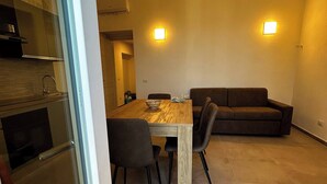 Een moderne woonruimte met een eettafel, stoelen, een bank en een keuken.