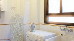 A laundry area with a washing machine, an iron, and a sink.
