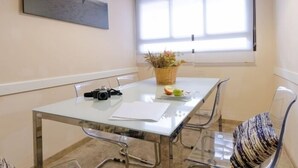 A modern meeting room with a glass table, metal chairs, a basket with fruit, and a camera on the table.