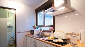 A modern kitchen with white cabinets, a wooden countertop, a built-in oven, and a window above the sink.