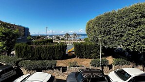 A parking area with cars, a view of a marina, and a clear blue sky. - Faro Porto Apartment 4 (Monte Argentario)