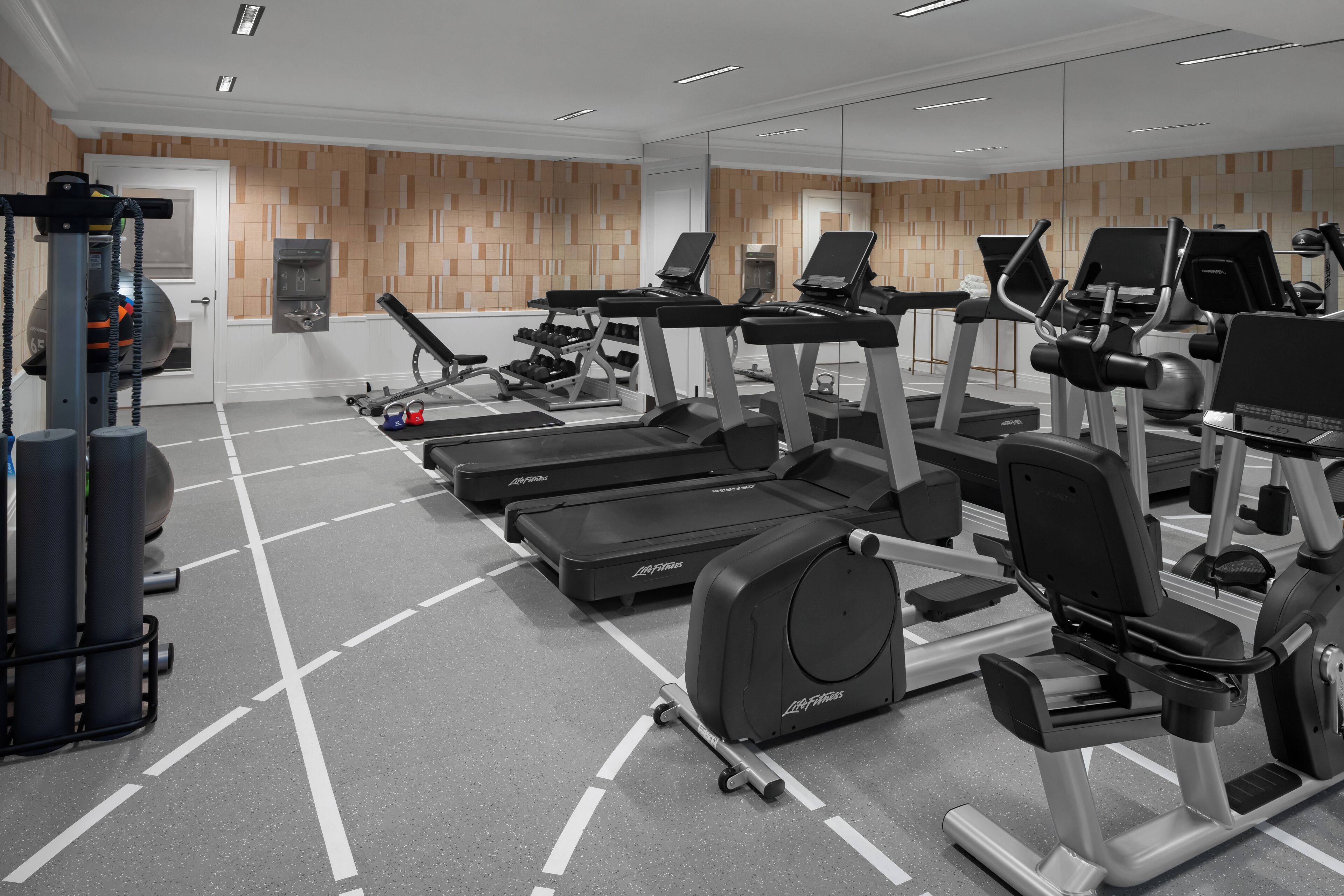 Un gimnasio moderno con cintas de correr, elípticas y equipo de pesas.