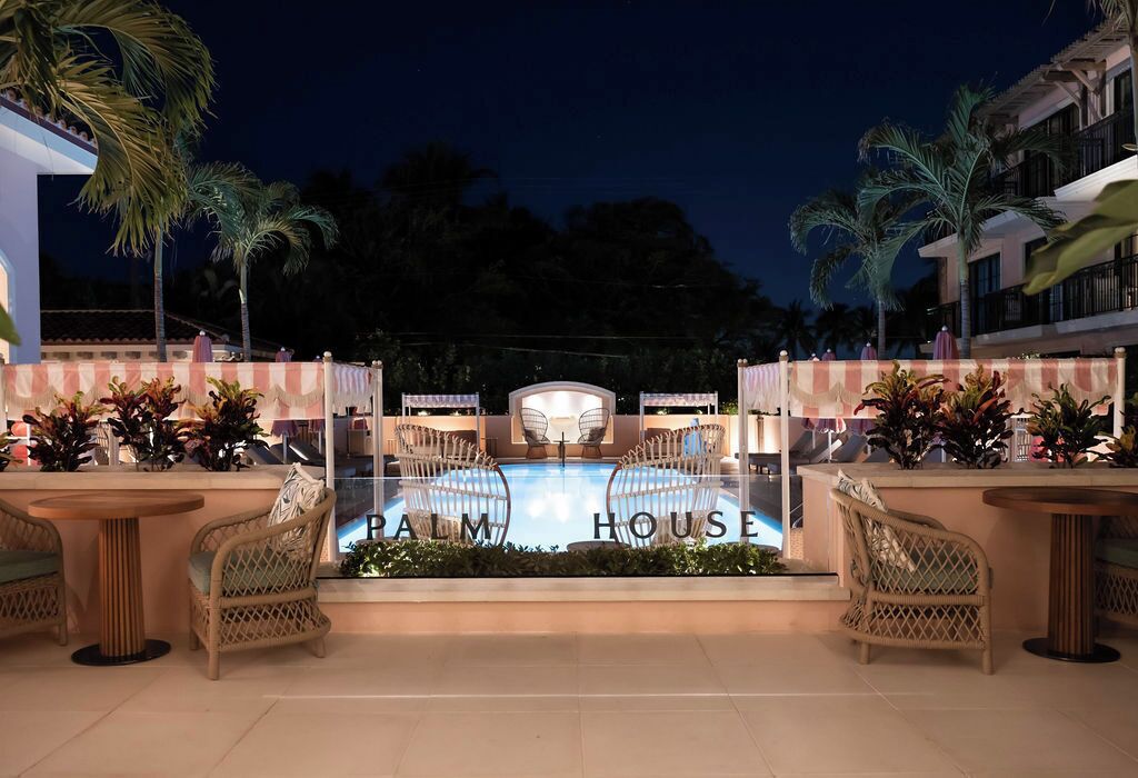 Un espace piscine avec des chaises longues et un panneau indiquant « PALM HOUSE ».