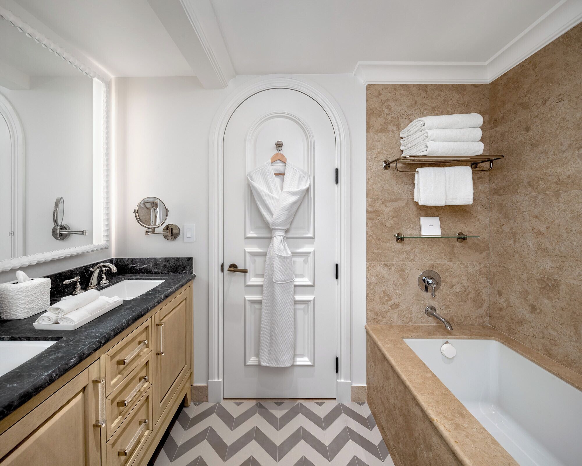 A modern bathroom with a marble sink, a bathtub, and a towel rack.